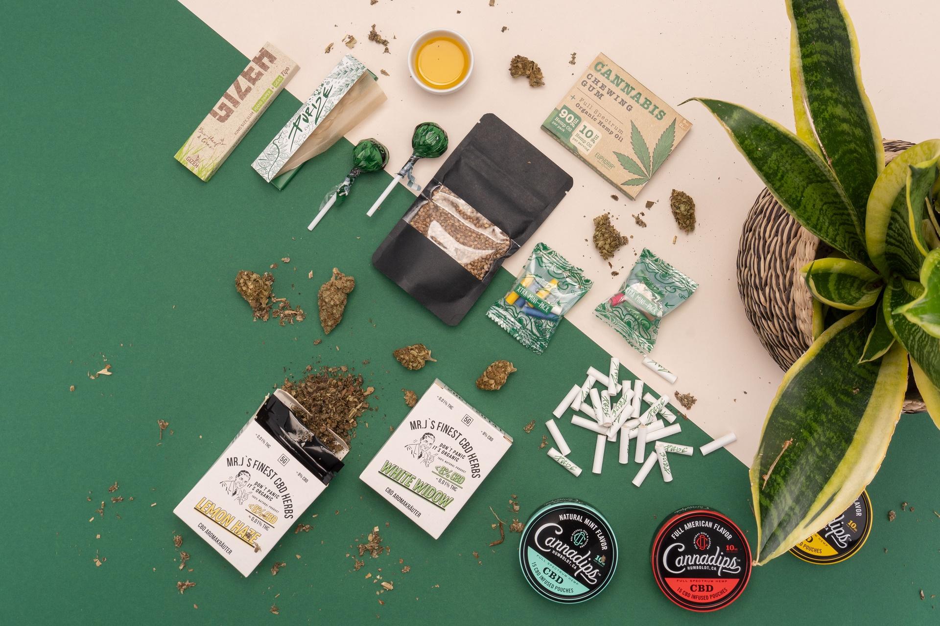 CBDoMat Teaser mit verschiedenen Produkten aus der Vogelperspektive auf beige-grünem Hintergrund