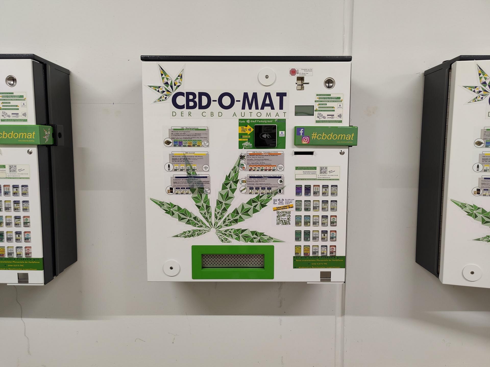 Foto eines CBD-Automaten an der Wand zwischen zwei anderen Automaten